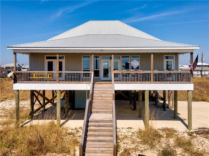 Brown beach house with porch and stairway down to beach. Illustrating blog post: What is property maintenance for Mobile, Alabama homeowners?